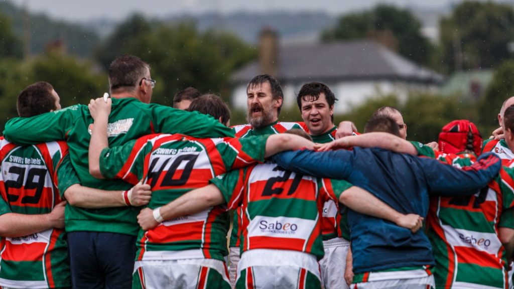 Mixed Ability rugby players with their arms around one another in a team huddle.